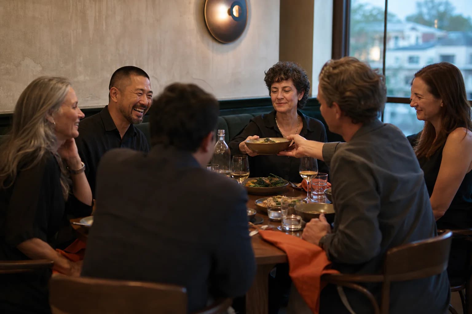 Six friends sharing dishes during a relaxed group dinner in an invented restaurant